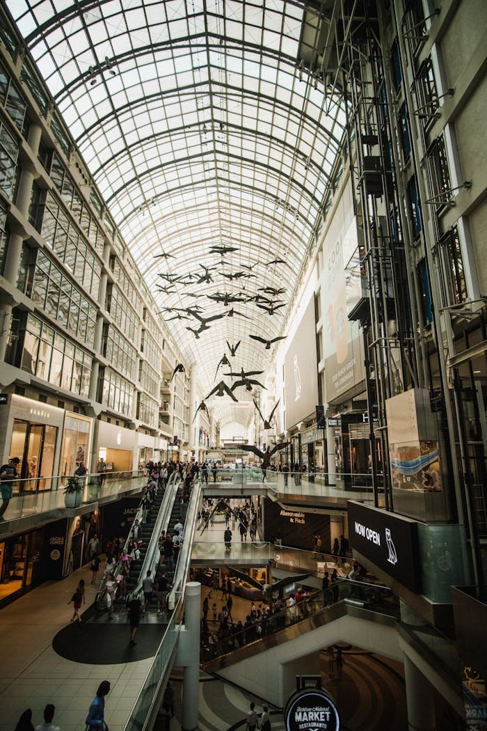 Wide-angle view of a bustling Toronto shopping center with glass dome ceiling.