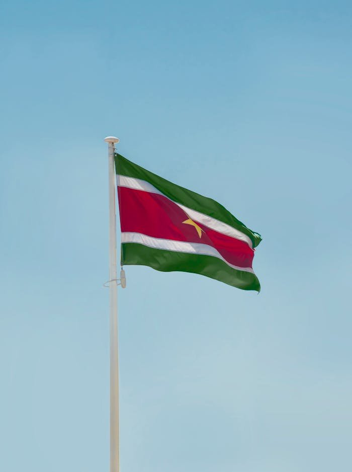 the-flag-of-suriname-13966908 The Suriname national flag waving against a clear blue sky in Paramaribo.